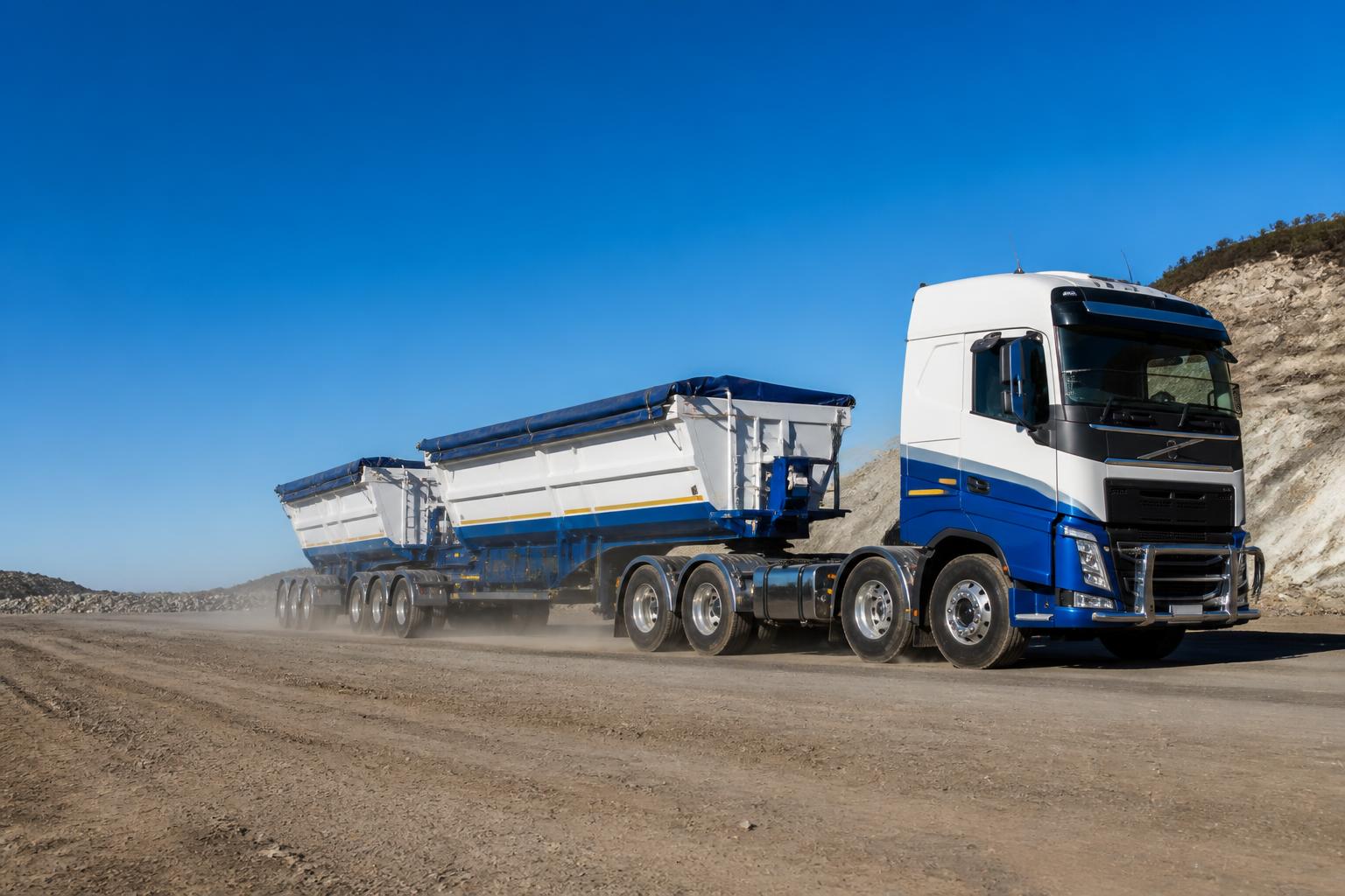 Blue and white side tipper truck travelling on a haul road